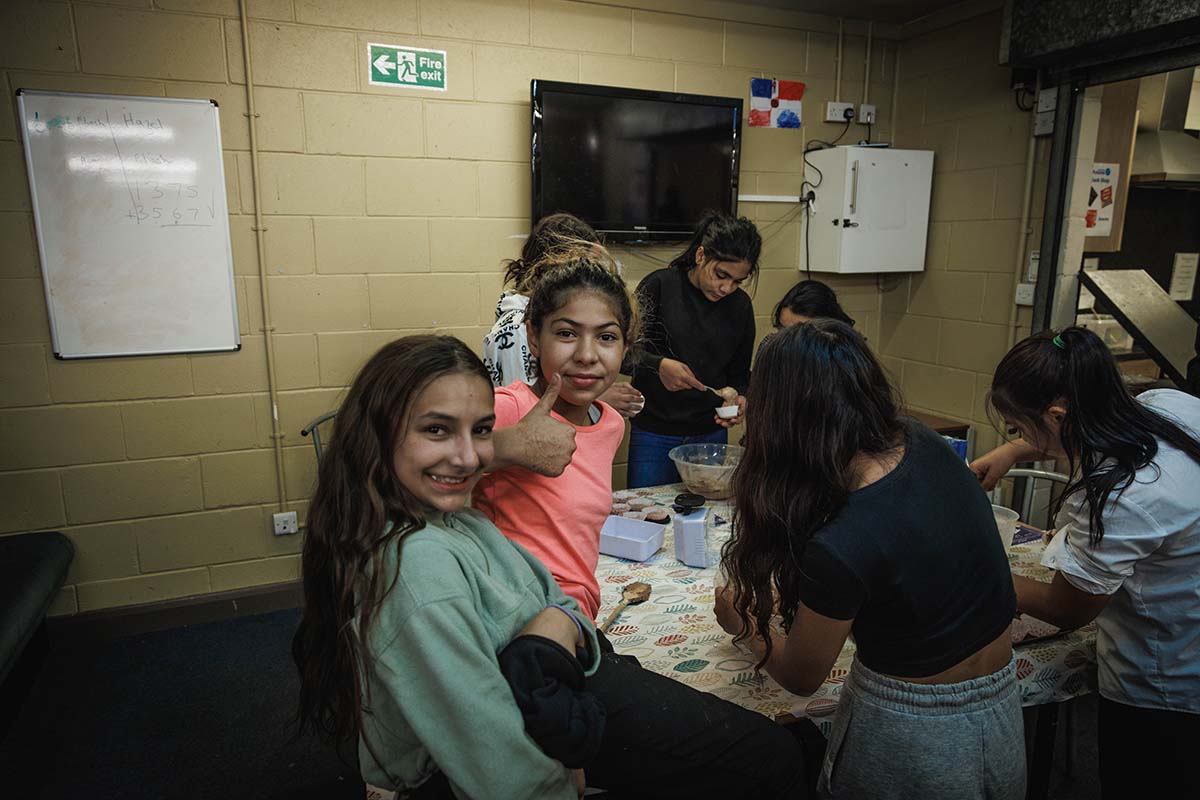 a group of young girls smile and put their thumbs up at the camera